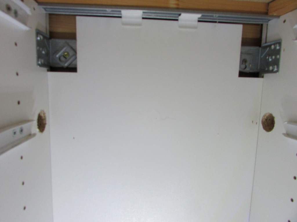 Back of a cupboard with two holes drilled in either side.