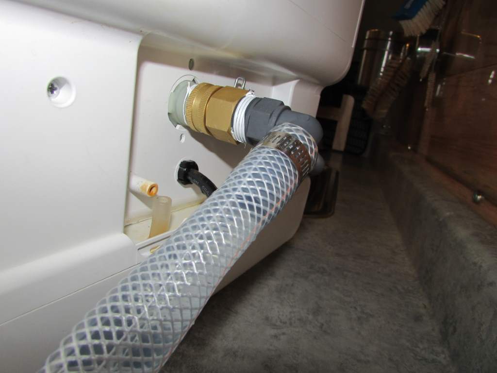 Close up of a hose attached to the back of a dishwasher.